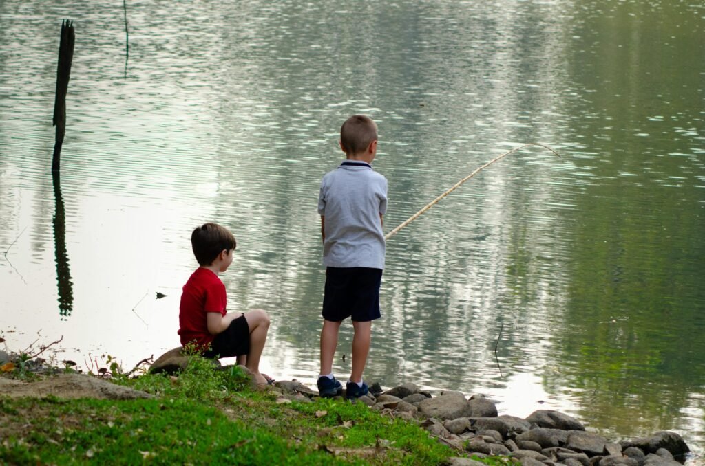Two boys fishing by a serene lake in Porto Feliz, Brazil, enjoying a summer day.